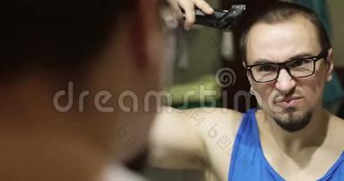 男人`在家里用电剪头剪头发。